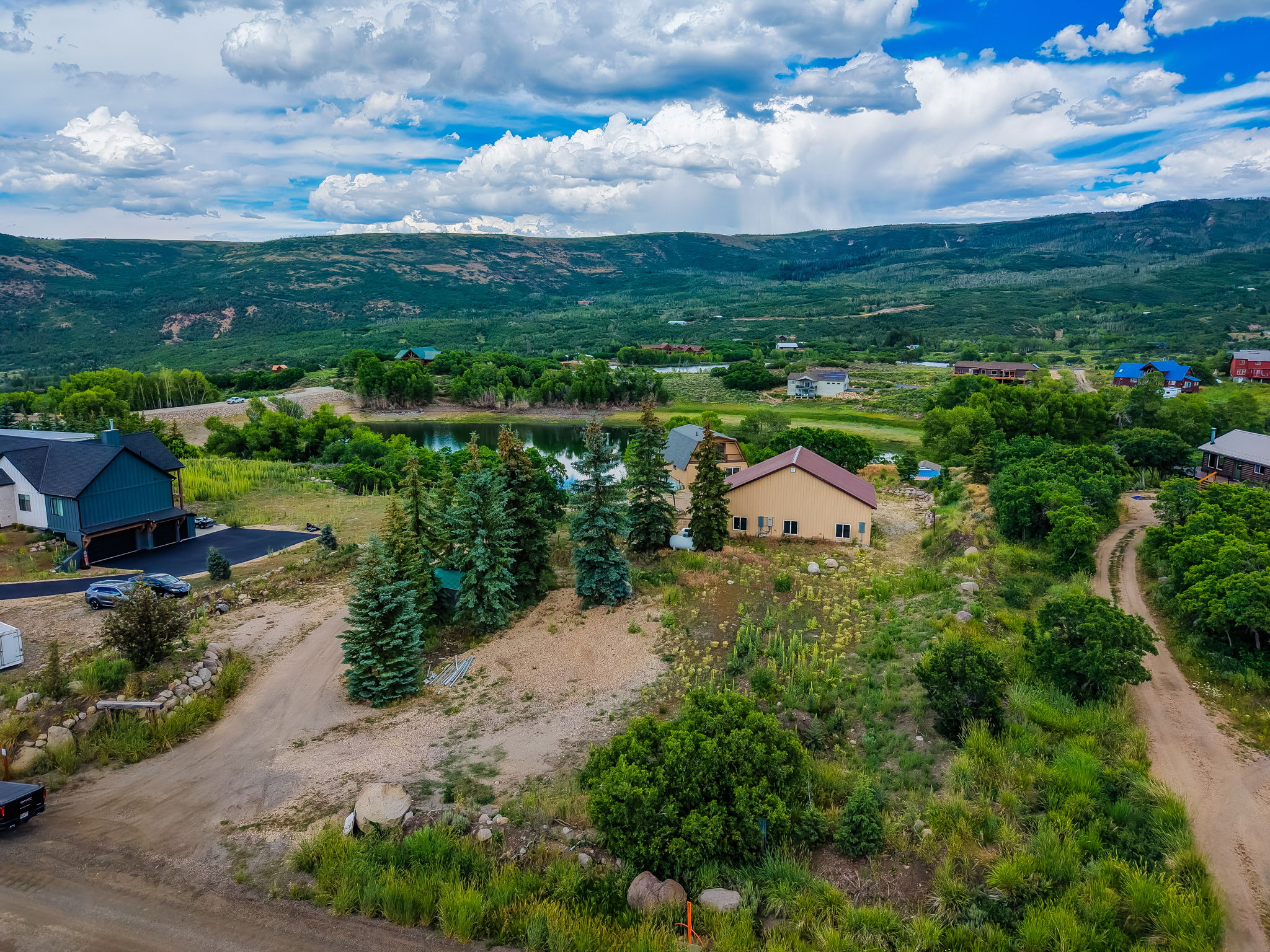 Expansive property with a verdant landscape, featuring a prominent pond, mature evergreen trees, and distant mountain scenery