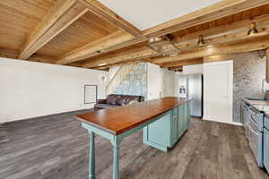 Dual tone kitchen featuring wood counters, a wood ceiling with exposed beams, stainless steel fridge with ice dispenser, a breakfast bar, and dark wood-style floors
