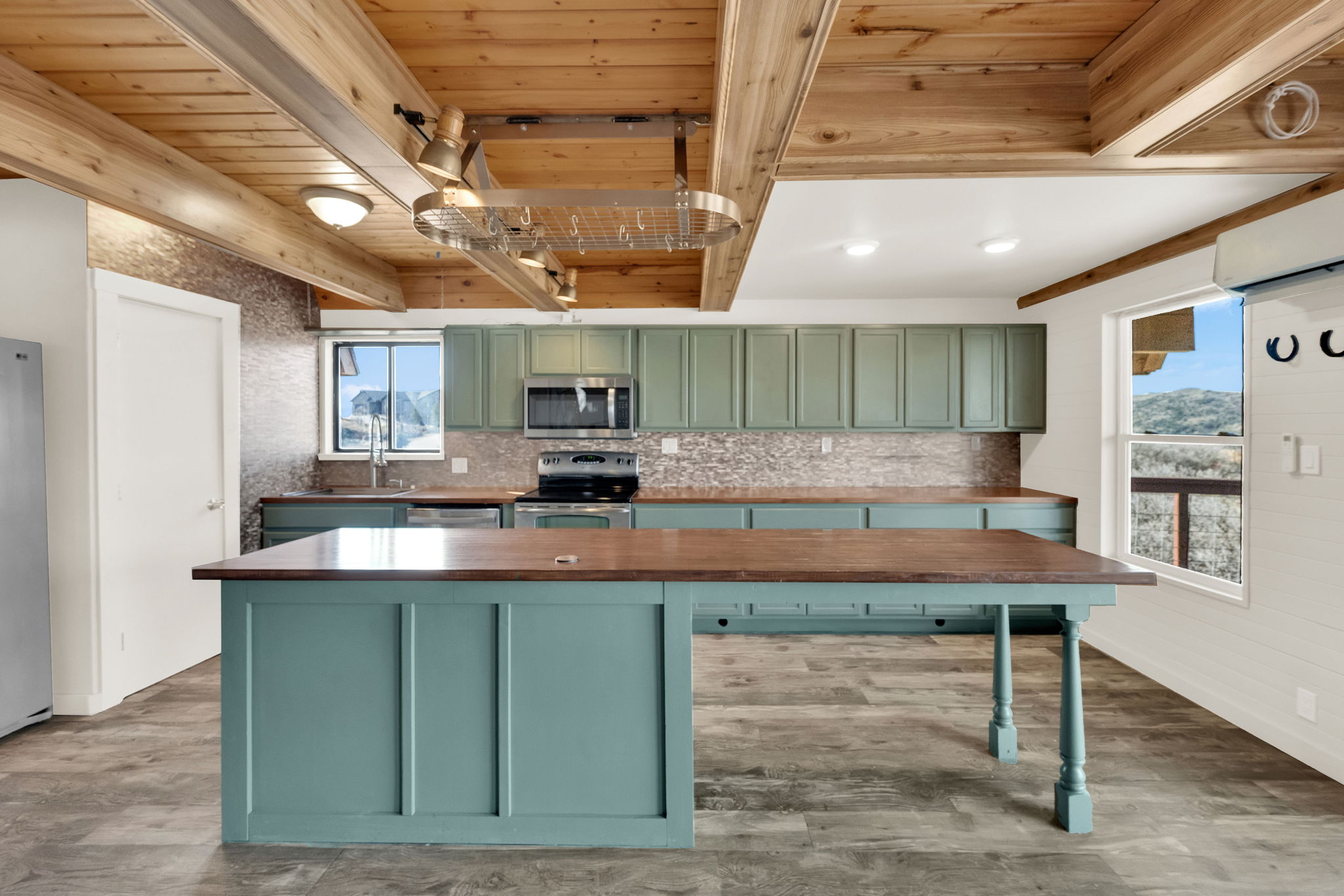 Kitchen featuring green cabinetry, wooden counters, stainless steel appliances, a wood ceiling with exposed beams, and light wood-type flooring