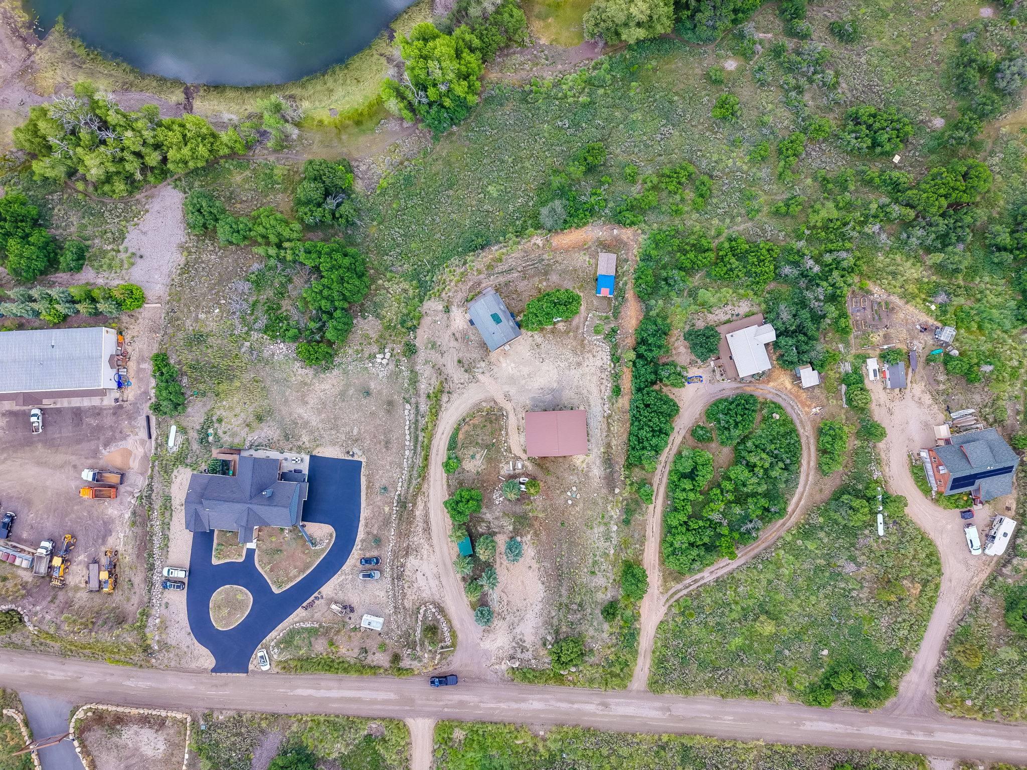 Spacious property featuring a large residence, circular paved driveway, and surrounding natural landscape