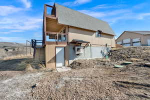 View of side of property with a shingled roof, a detached garage, a balcony, and an outbuilding