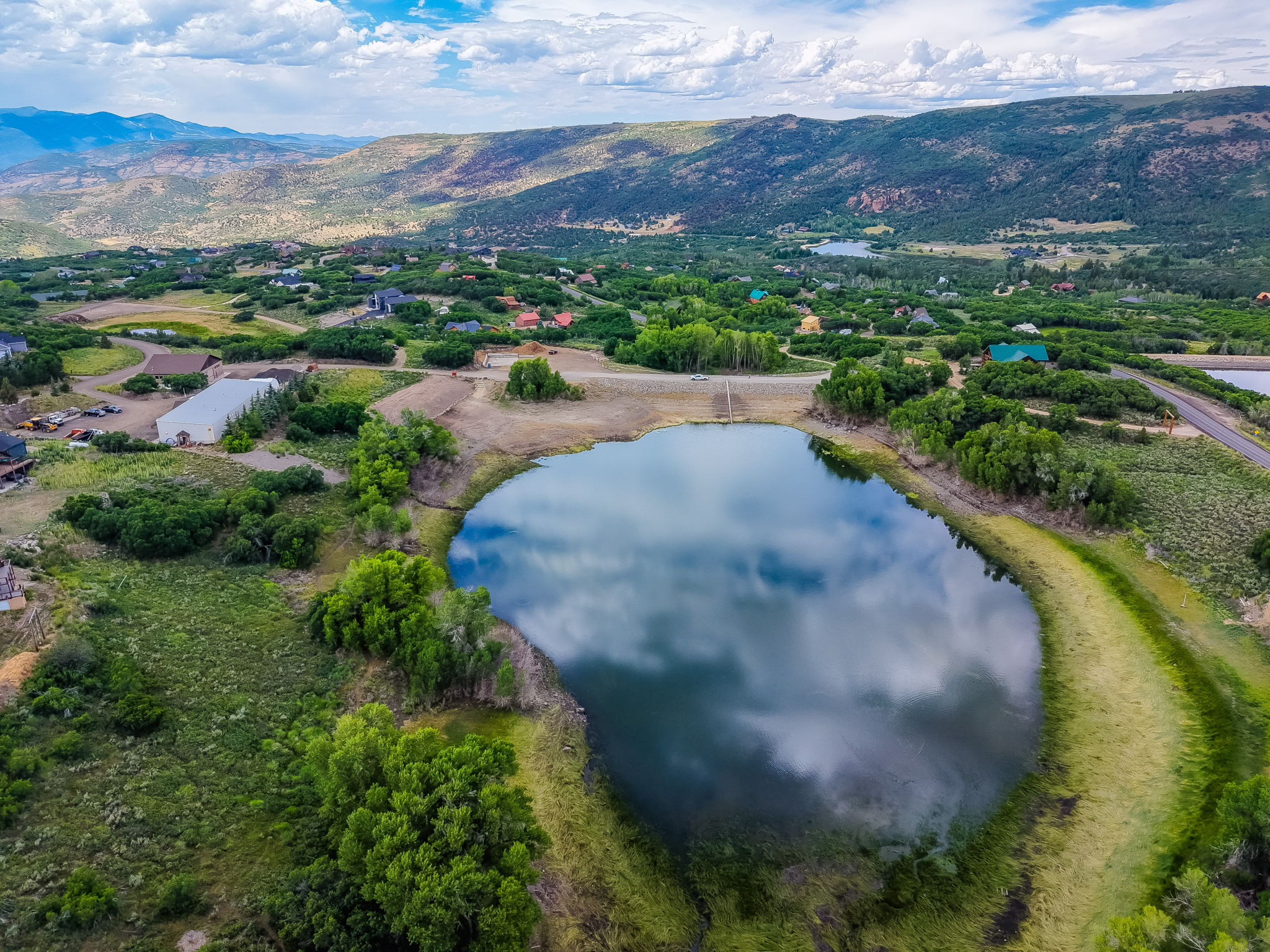 Lakeside community featuring multiple water bodies, lush green vegetation, mountainous terrain, and scattered residential properties