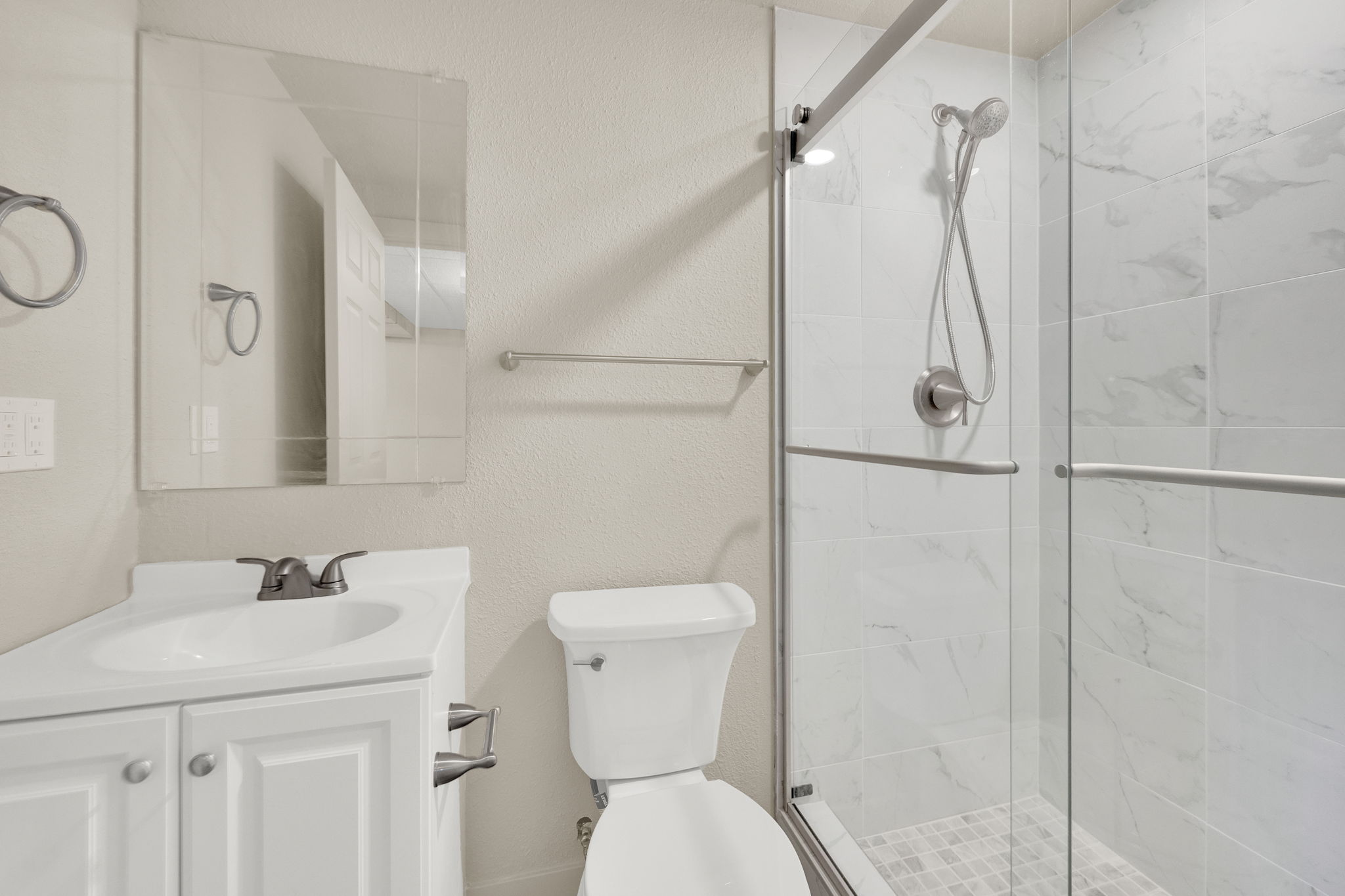 Full bathroom featuring a textured wall, vanity, and a shower stall