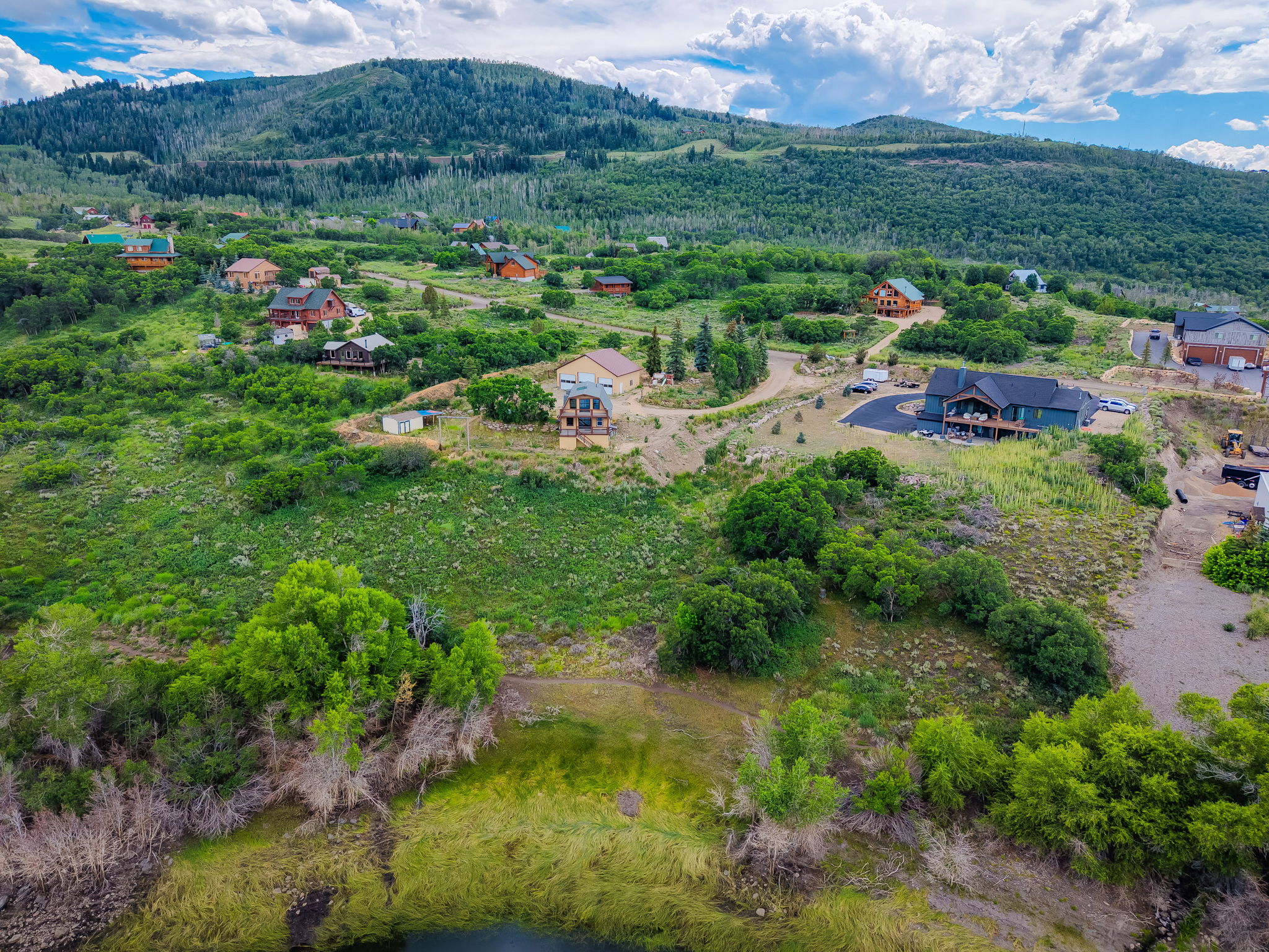 Elevated property featuring a natural terrain, verdant foliage, distant mountain backdrop, and a body of water