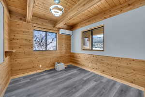 Empty room featuring wood walls, a wainscoted wall, a wood ceiling with exposed beams, wood finished floors, and plenty of natural light