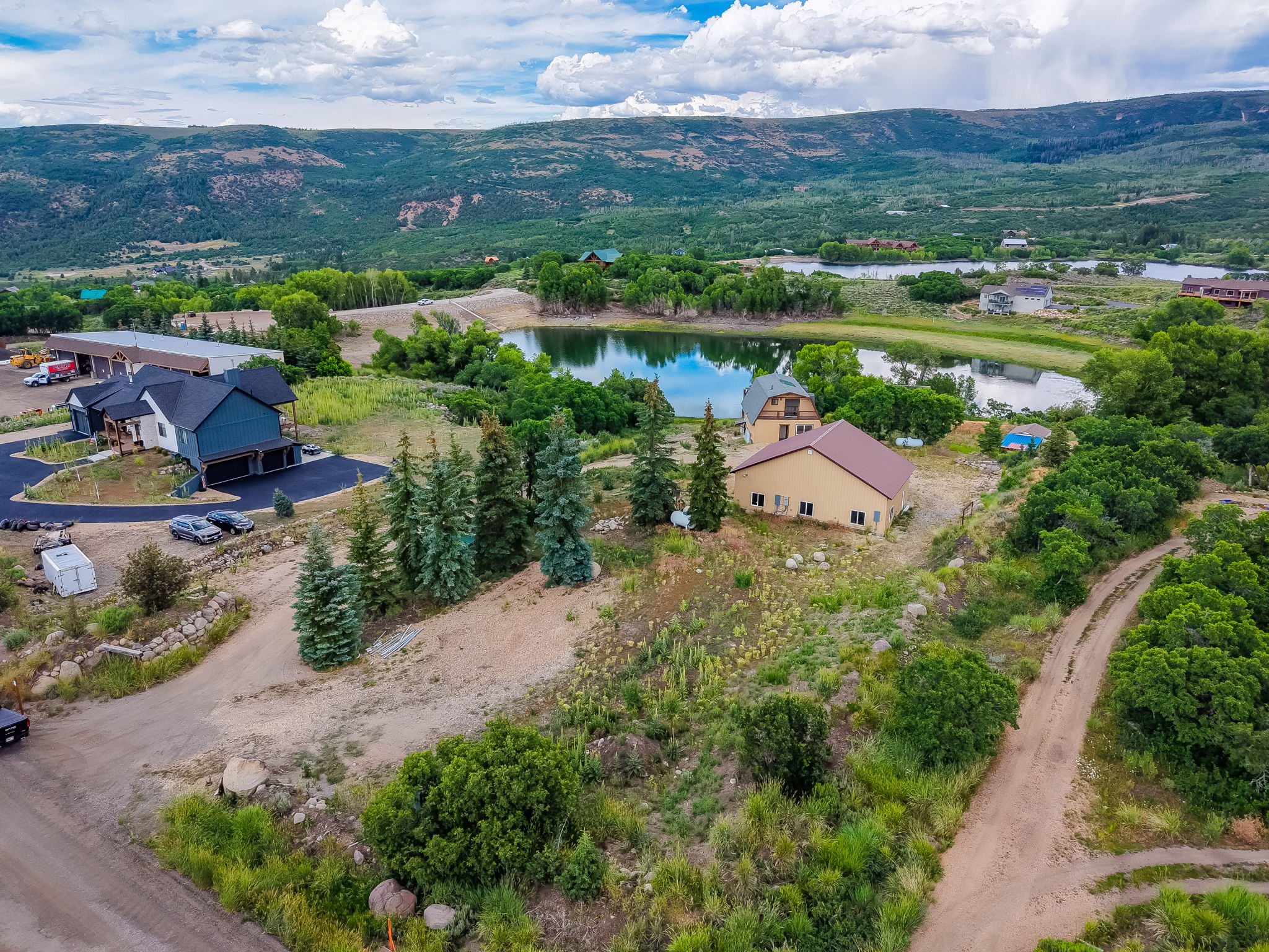 Expansive property featuring multiple structures, including a prominent blue-sided residence with an attached garage and paved driveway