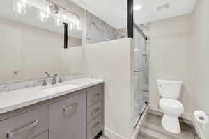Full bathroom with vanity, a marble finish shower, and light wood-type flooring