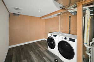 Laundry room with dark wood finished floors and washer and clothes dryer