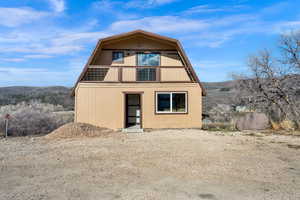 View of front of property featuring a gambrel roof, a balcony, and a mountain view