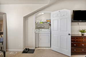Laundry room with light colored carpet and washing machine and clothes dryer