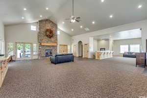 Living area with a high ceiling, a fireplace, carpet, a ceiling fan, and recessed lighting