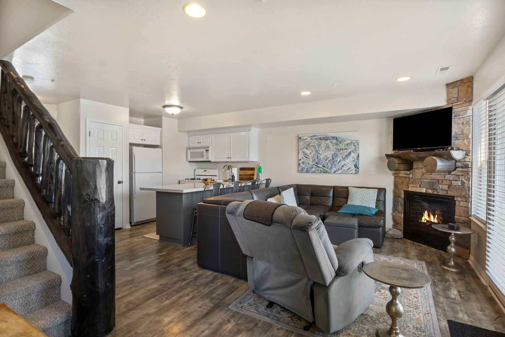 Living room with dark wood-style flooring, a stone fireplace, and recessed lighting