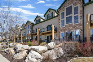 Back of house featuring stone siding and a balcony