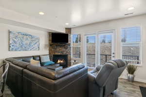 Living room with wood finished floors, a fireplace, and recessed lighting