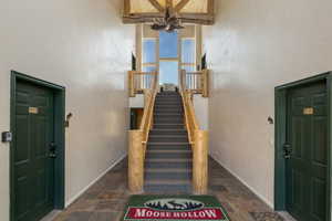 Staircase featuring stone finish flooring, a high ceiling, and a textured wall