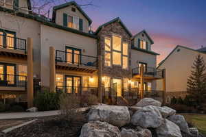 Rear view of house featuring stone siding and a balcony