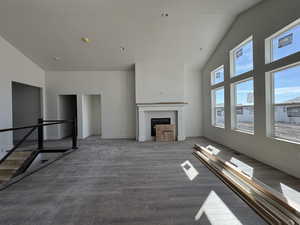 Unfurnished living room with lofted ceiling, dark wood-style floors, a tile fireplace, and recessed lighting