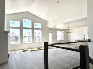 Rec room with light wood-style floors, a chandelier, and a high textured ceiling
