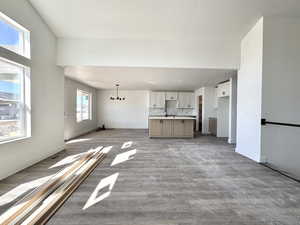 Unfurnished living room with wood finished floors and a chandelier