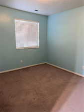 Spare room featuring dark carpet and baseboards