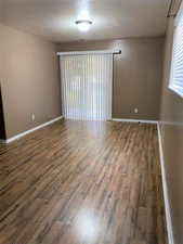 Unfurnished room with dark wood-style flooring and a textured ceiling