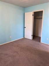 Unfurnished bedroom featuring dark carpet and a closet