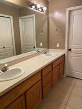 Full bathroom with double vanity and light tile patterned floors