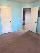 Unfurnished bedroom featuring dark colored carpet and baseboards