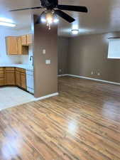 Kitchen featuring light countertops, ceiling fan, light wood-style flooring, white dishwasher, and wood finish cabinets