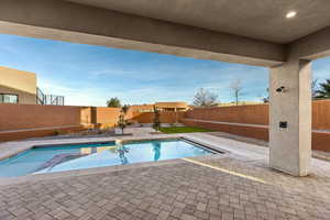 View of swimming pool with patio surround, a fenced backyard, and a jacuzzi