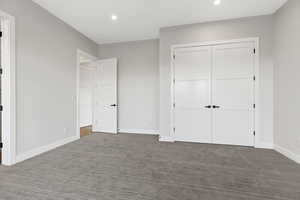 Unfurnished bedroom with dark carpet, recessed lighting, and a closet