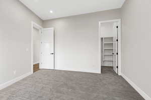 Unfurnished bedroom featuring a walk in closet, carpet, and recessed lighting