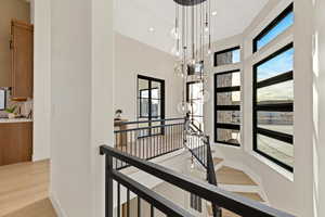 Hall featuring light wood-style floors, an upstairs landing, and hanging lights