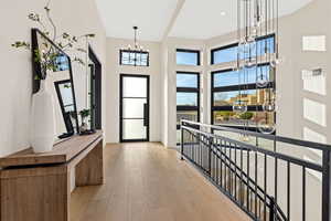 Foyer with light wood-style flooring, suspended lighting, and a high ceiling