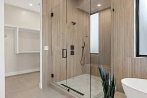 Full bath with a stall shower, a freestanding tub, a spacious closet, light tile patterned floors, and recessed lighting