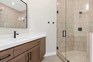 Full bathroom with a stall shower, vanity, and light tile patterned flooring