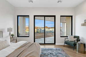 Bedroom with light wood-type flooring, a residential view, and access to outside