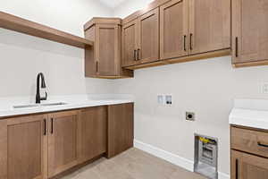 Laundry area featuring hookup for a washing machine, light tile patterned floors, electric dryer hookup, and cabinet space
