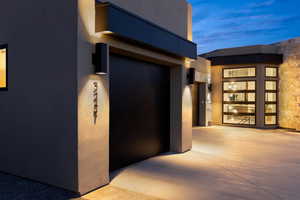 Exterior entry at dusk featuring stucco siding and stone siding