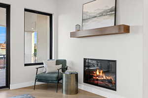 Sitting room featuring a glass covered fireplace and light wood-style floors