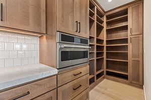 Kitchen with stainless steel oven, light wood finished floors, and light stone countertops