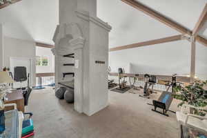 Exercise room with a fireplace, carpet flooring, and vaulted ceiling