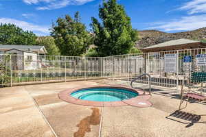 View of swimming pool featuring a community hot tub, a mountain view, patio surround, and a swimming pool