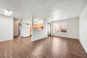 Unfurnished living room featuring dark wood-style floors and baseboards