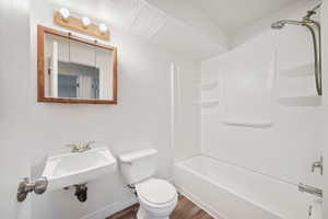Full bath featuring dark wood-style floors and shower / washtub combination