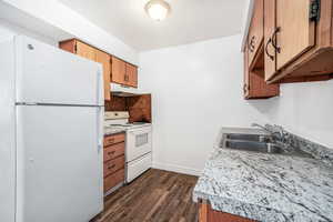 Kitchen featuring white appliances, light countertops, dark wood finished floors, and wood finish cabinets