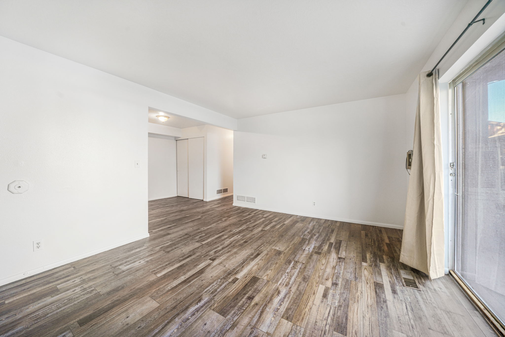 Spare room with dark wood-style floors and baseboards