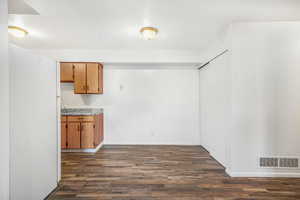 Unfurnished dining area with dark wood-type flooring and a textured ceiling