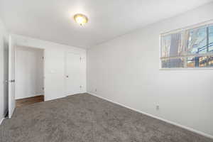 Unfurnished bedroom featuring baseboards and dark colored carpet