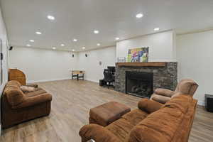 Living room with a stone fireplace, light hard flooring, and recessed lighting